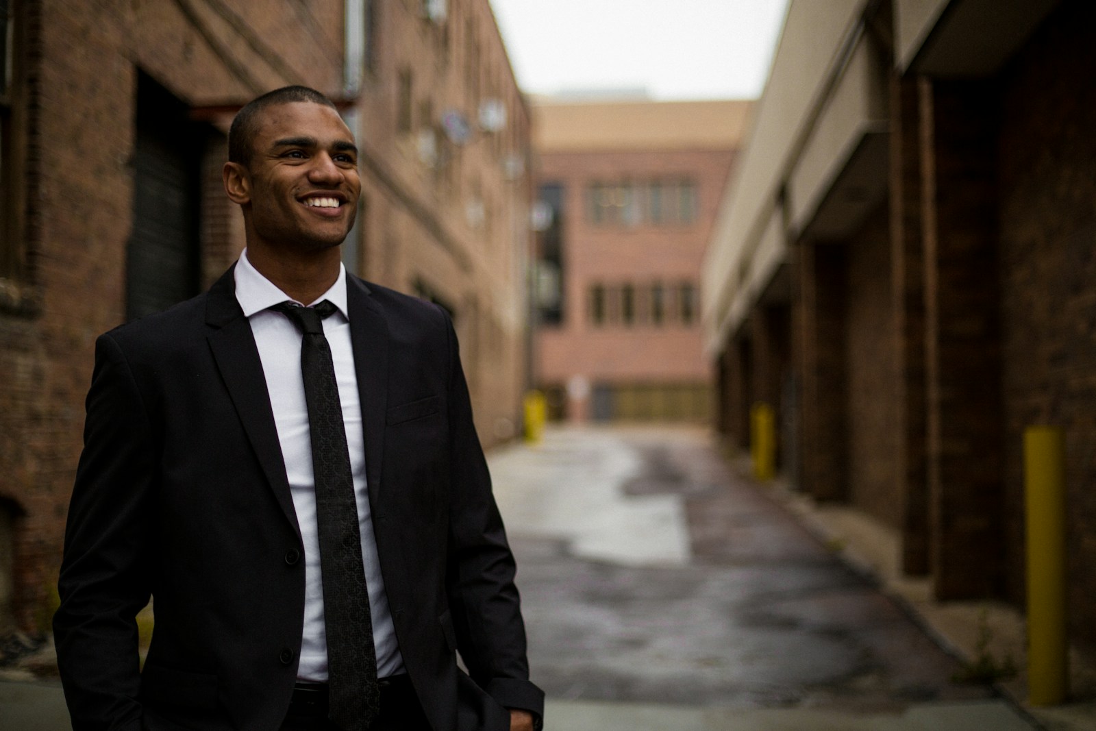 smiling man standing between brown concrete buildings with business property insurance at daytime